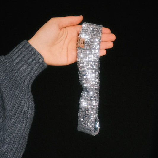 Basic Haarband Pailletten Silberglanz in der Hand gehalten mit schimmerndem Stoff dieHaarbanduschi