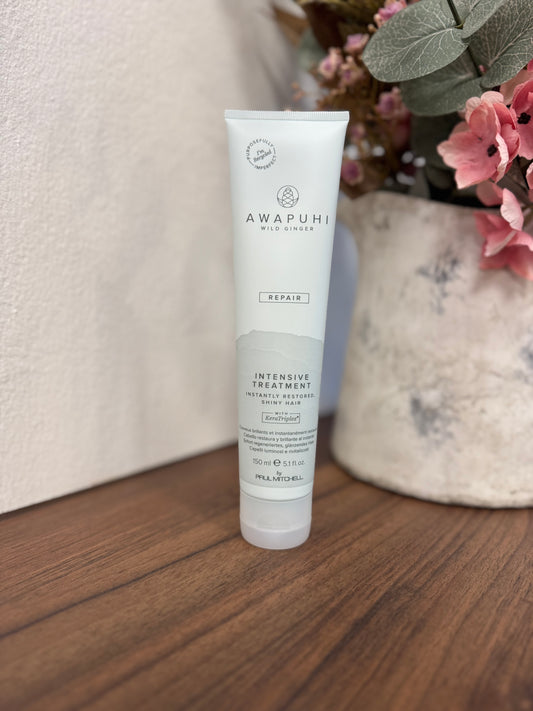 Awapuhi Wild Ginger Intensive Treatment Maske, Tube frontal auf Holztisch mit Blumen – Paul Mitchell