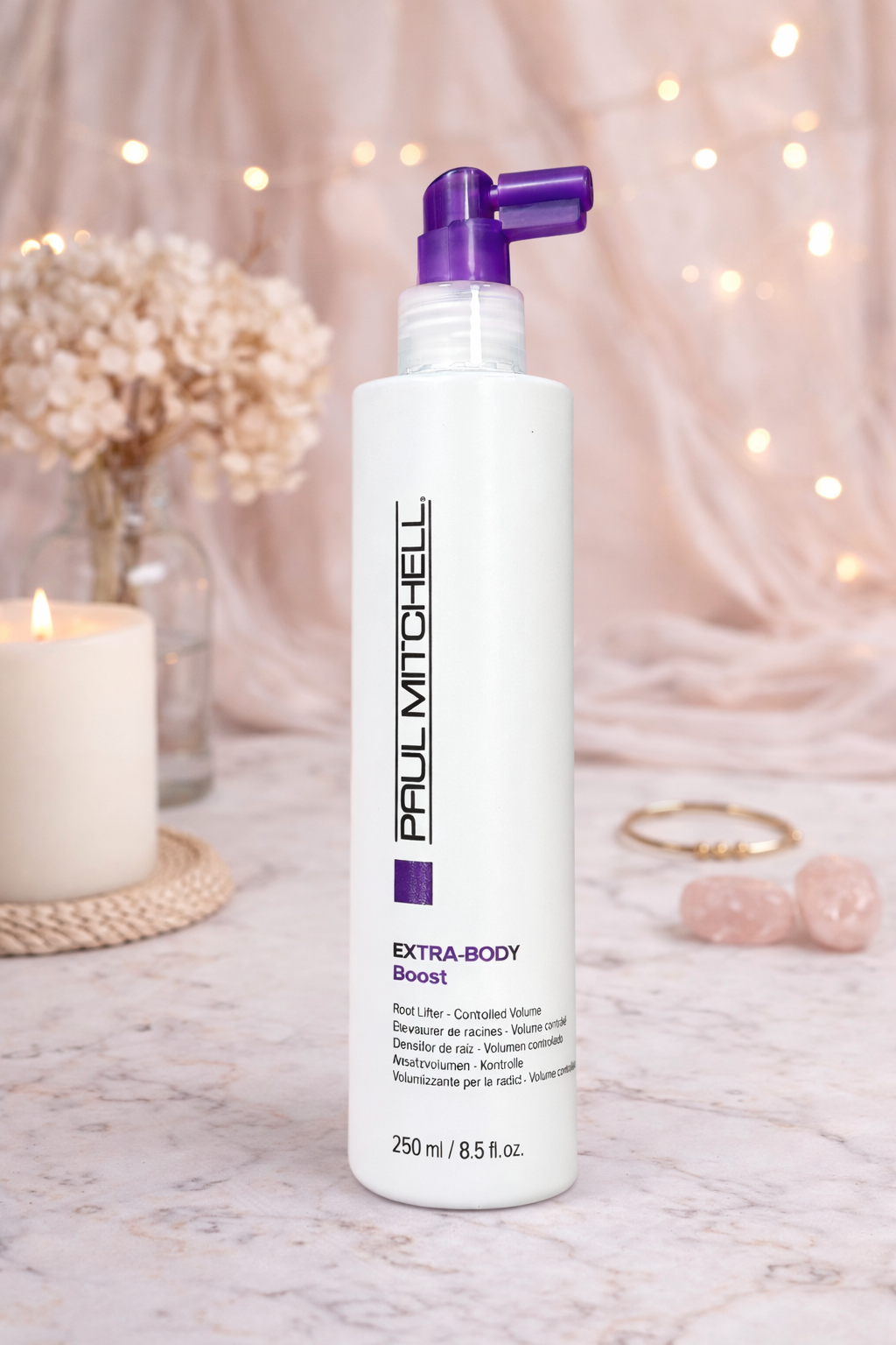 Ansatz Volumenspray Extra Body Boost dekorativ auf Marmoroberfläche mit Kerze und Deko in sanfter Atmosphäre, Paul Mitchell