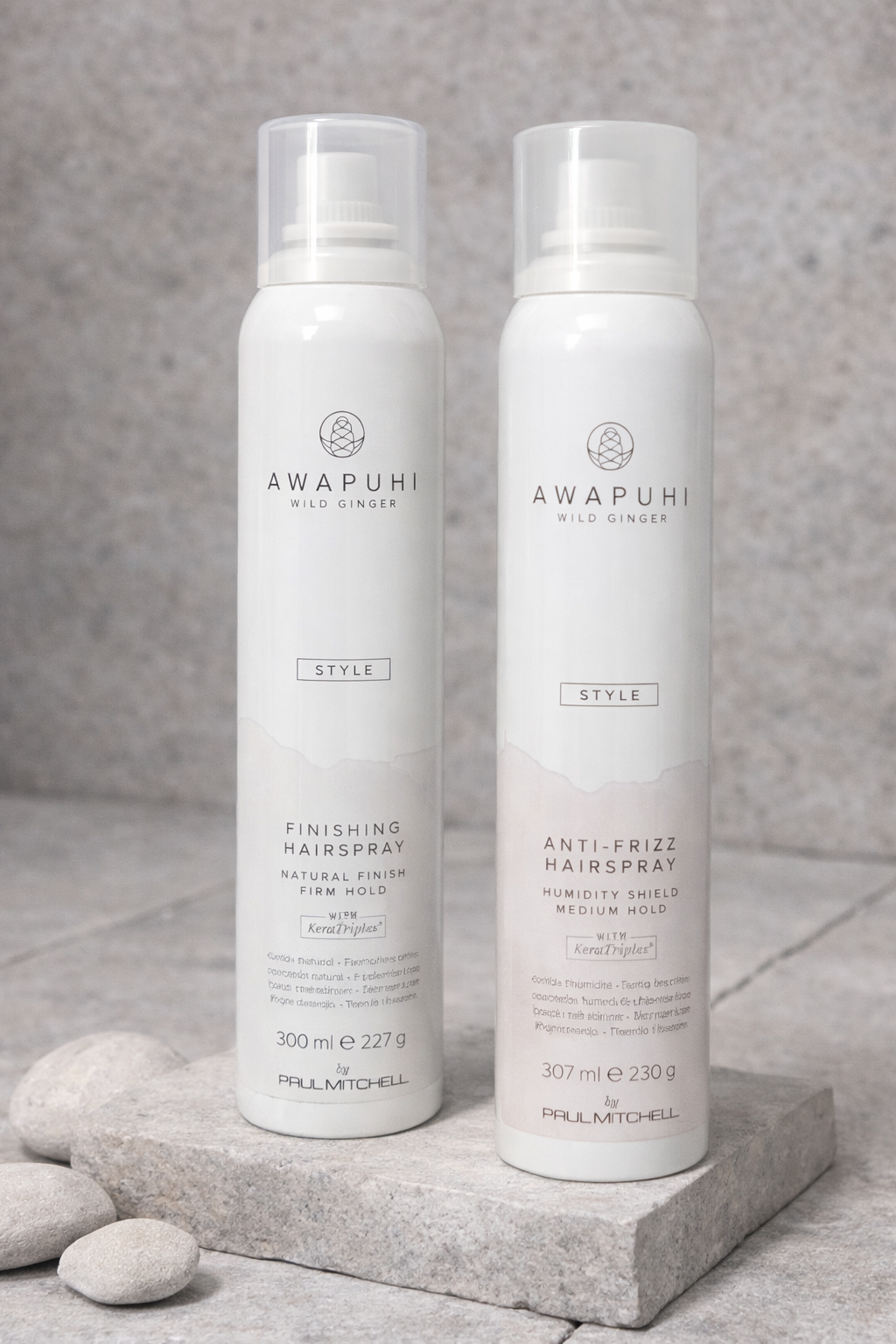 Finishing und Anti Frizz Hairspray nebeneinander auf Steinpodesten arrangiert – Paul Mitchell