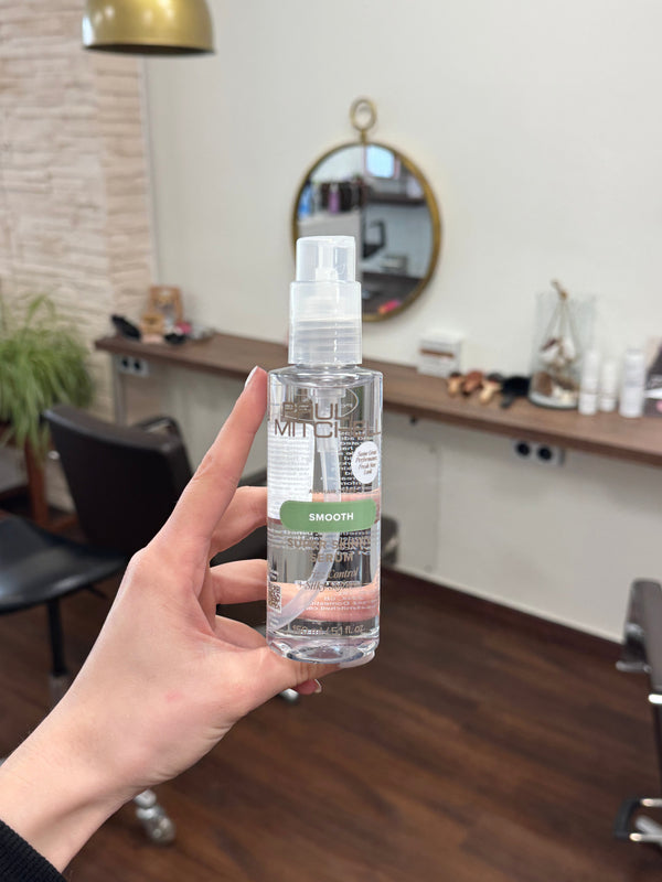 Paul Mitchell Super Skinny Serum Frizz Kontrolle glättendes Haarserum 150 ml transparentes Stylingserum Flasche in der Hand gehalten im FriseursalonPaul Mitchell