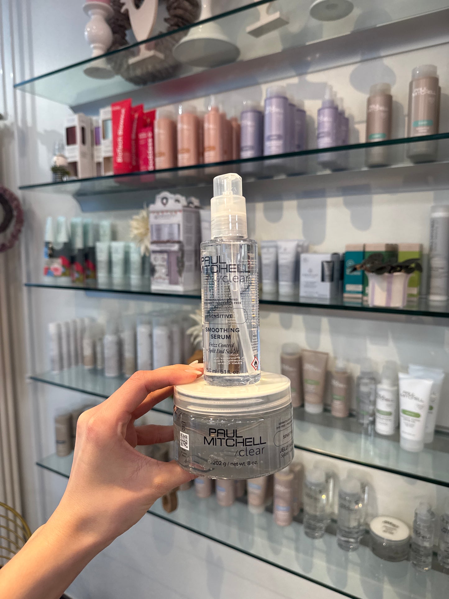 Smoothing Serum und Jelly Mask für empfindliche Kopfhaut in Hand vor Produktregal im Salon – Paul Mitchell