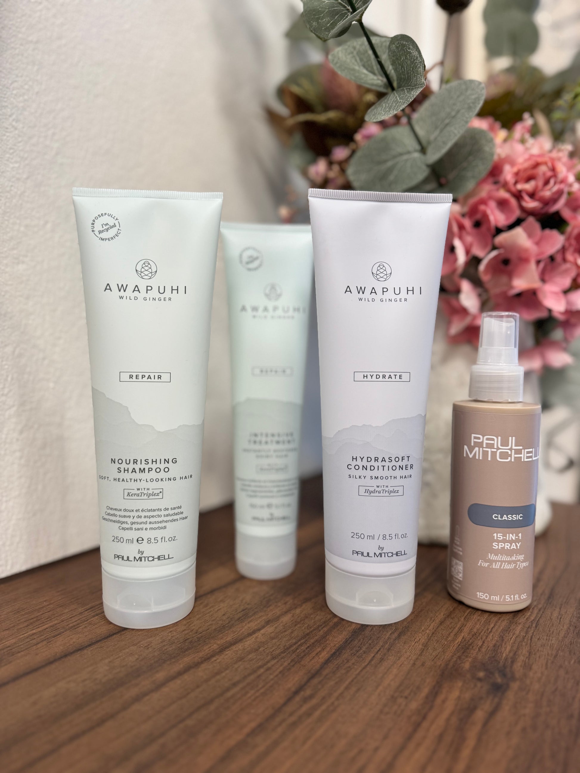 Awapuhi Wild Ginger Repair Set blondiertes Haar, vier Produkte nebeneinander auf Holztisch – Paul Mitchell