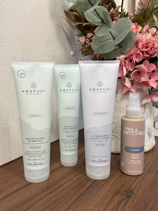 Awapuhi Wild Ginger Repair Set blondiertes Haar, vier Produkte nebeneinander auf Holztisch – Paul Mitchell