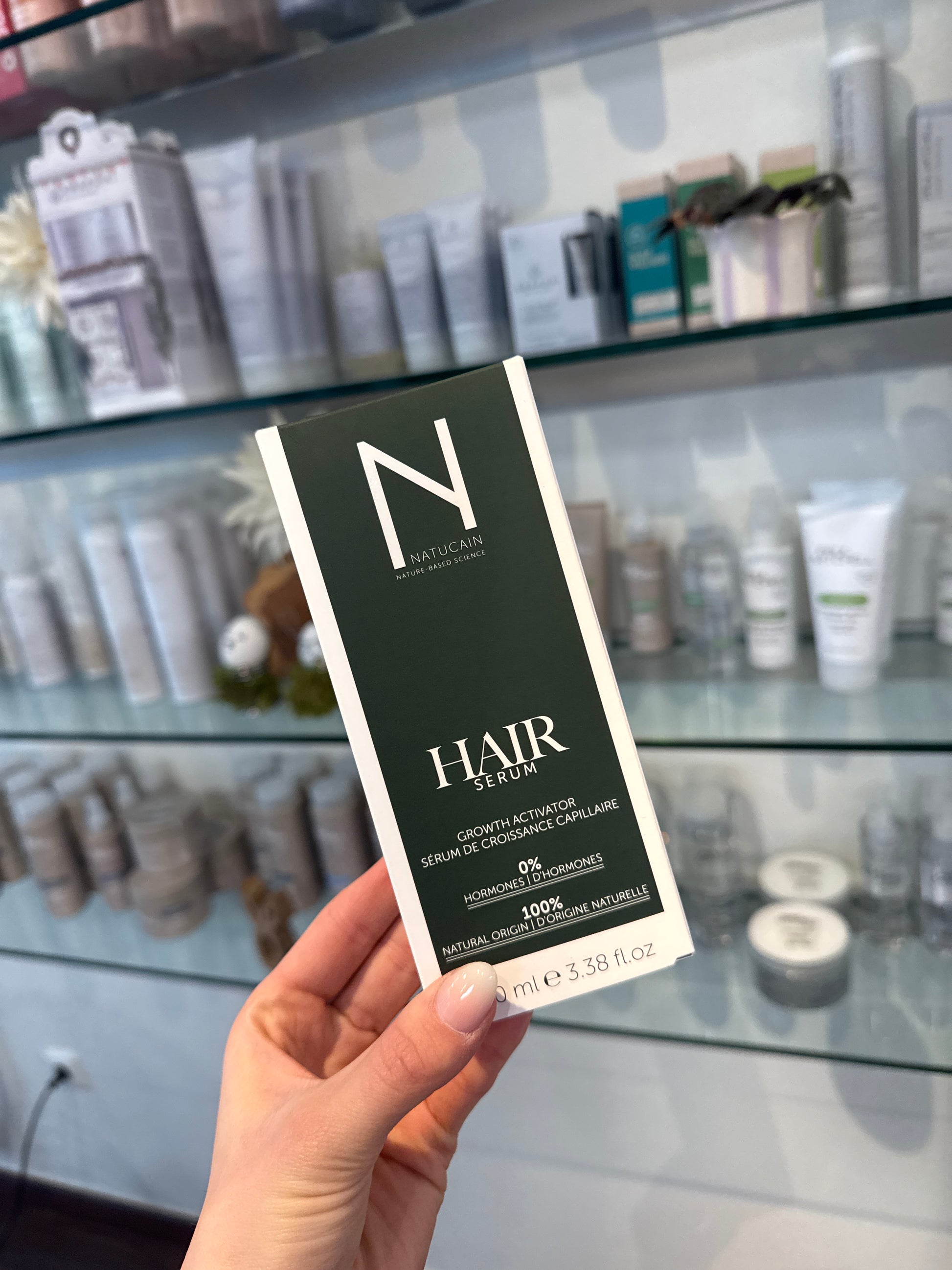 Haarserum Natucain Growth Activator Verpackung 100 ml in Hand vor Salonregal – Natucain