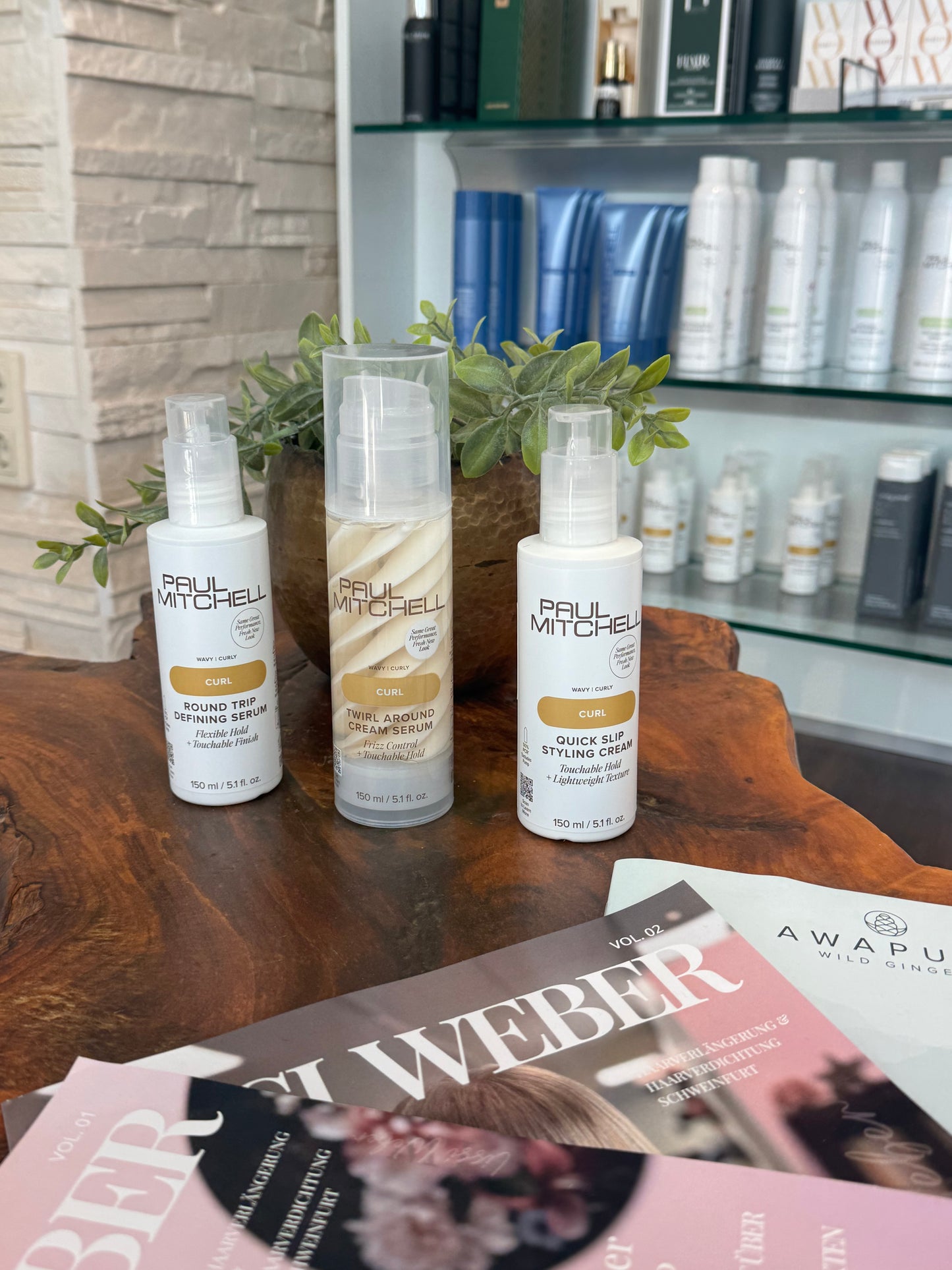     Paul Mitchell Curl Styling Produkte – Round Trip Defining Serum, Twirl Around Cream Serum und Quick Slip Styling Cream auf Holztisch – Paul Mitchell