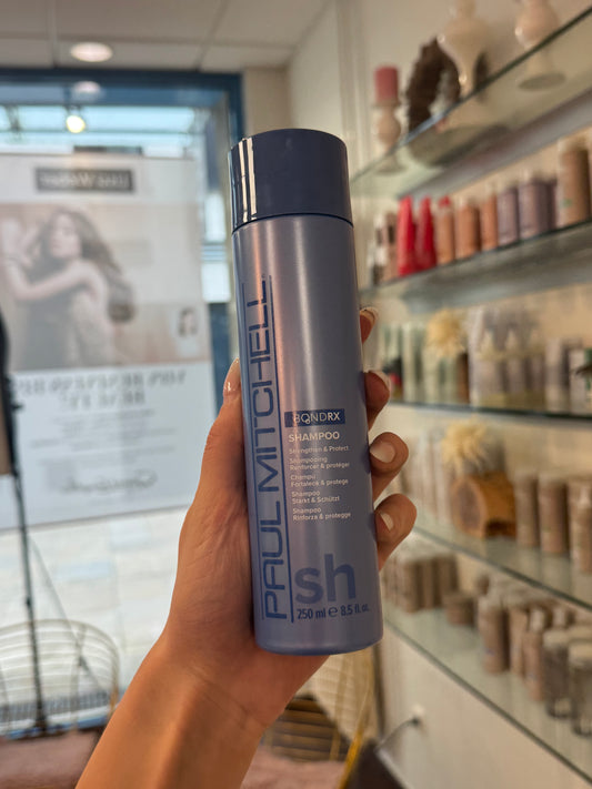 Bond Rx Shampoo für geschädigtes Haar, blaue Flasche wird im Salon in der Hand gehalten – Paul Mitchell