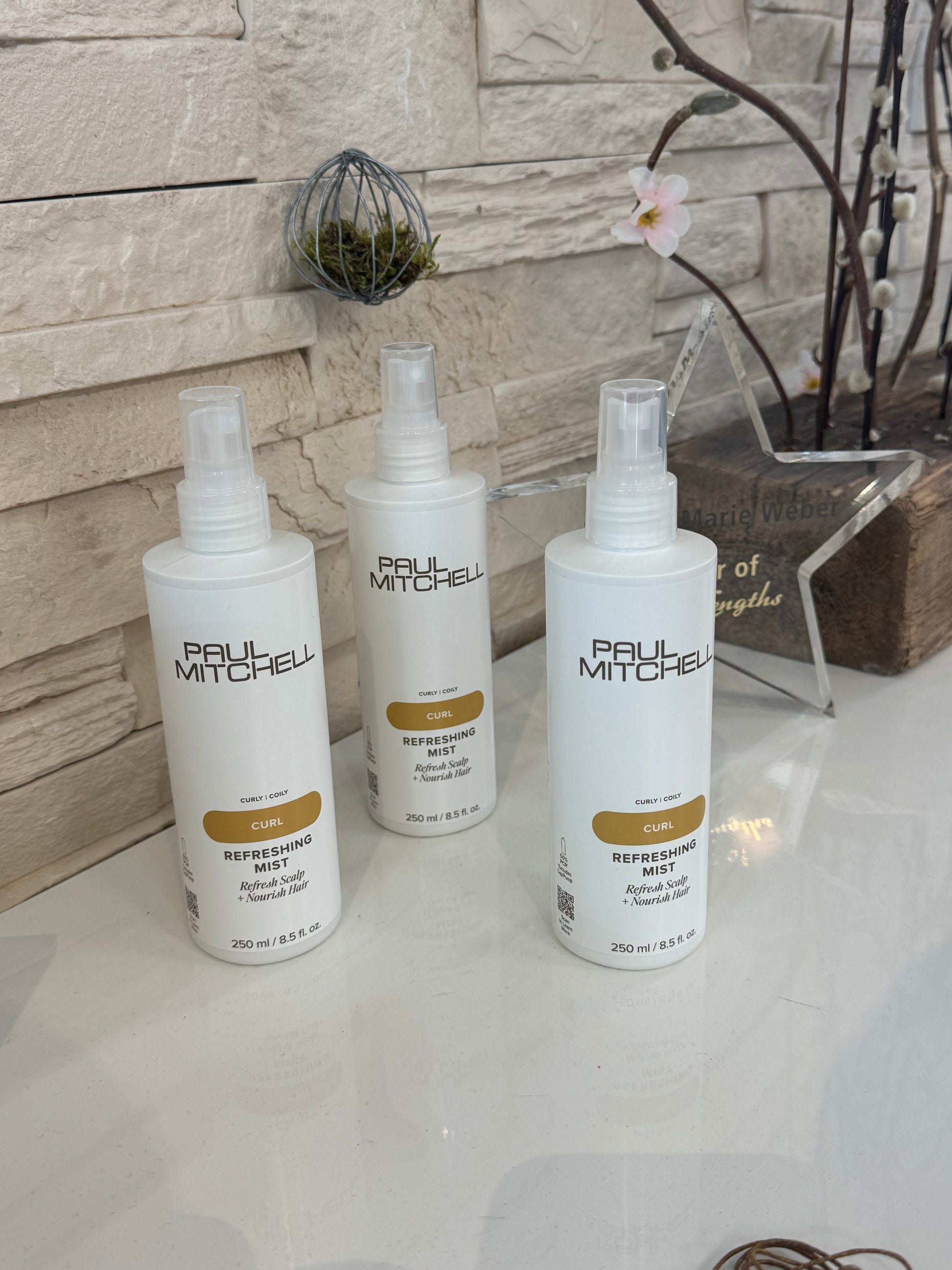 Paul Mitchell Curl Refreshing Mist – Drei Locken Auffrischungssprays auf Theke im Friseursalon präsentiert – Paul Mitchell