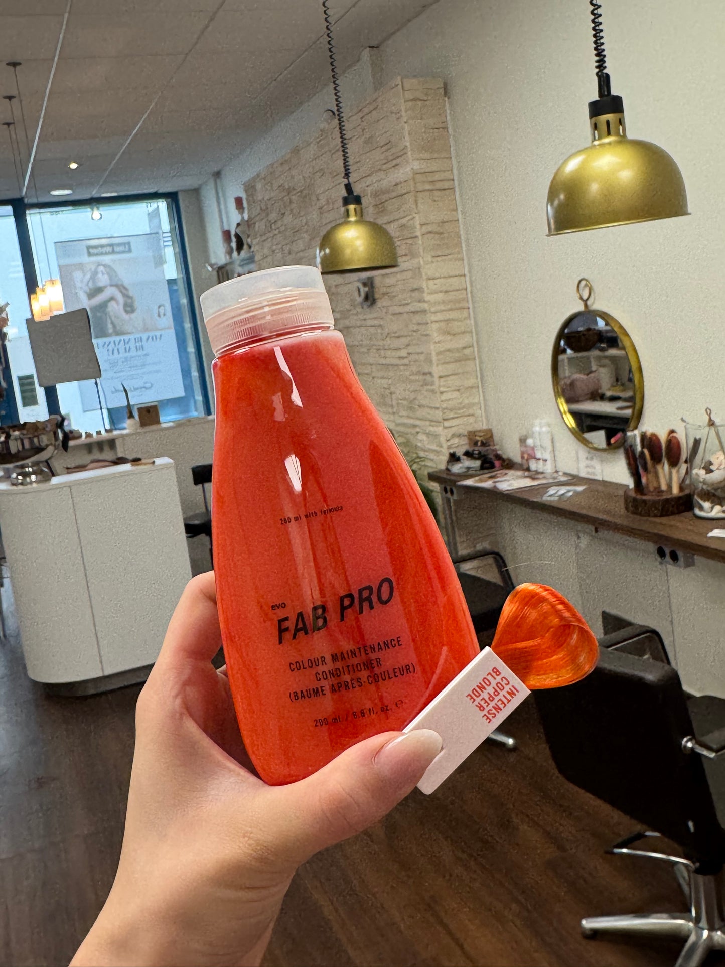 FAB Pro Conditioner kupferroter Farbton mit Farbmuster im Friseursalon, intensive Farbpflegeflasche in der Hand – Evo
