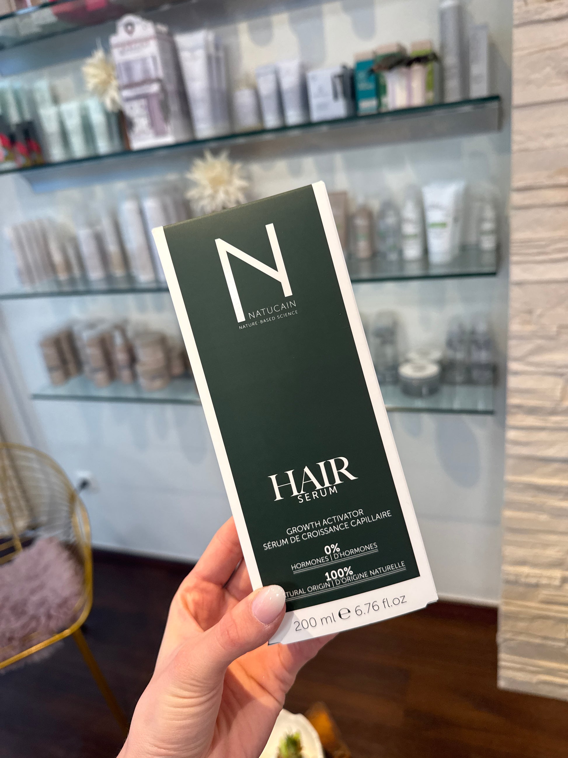 Haarserum Natucain Growth Activator Verpackung 200 ml in Hand vor Produktwand – Natucain
