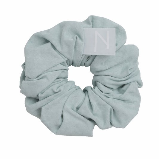 Haarschonender Scrunchie aus Bambusseide in Pastellblau mit Stofflabel freigestellt auf weißem Hintergrund