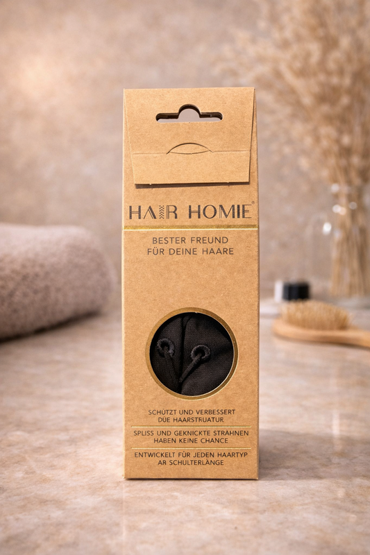 HairHOMIE Haarschutz gegen Spliss, Produktverpackung stehend in natürlichem Spa Setting mit Handtuch und Bürste im Hintergrund – HairHOMIE