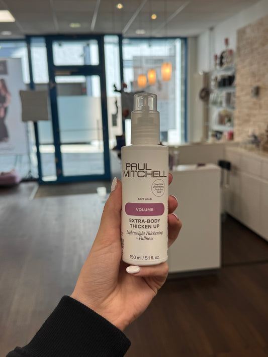 Paul Mitchell Extra-Body Thicken Up Stylingcreme für mehr Haarfülle, weiße Pumpflasche für feines Haar gehalt in der Hand im Salon Lissi Weber – Paul Mitchell