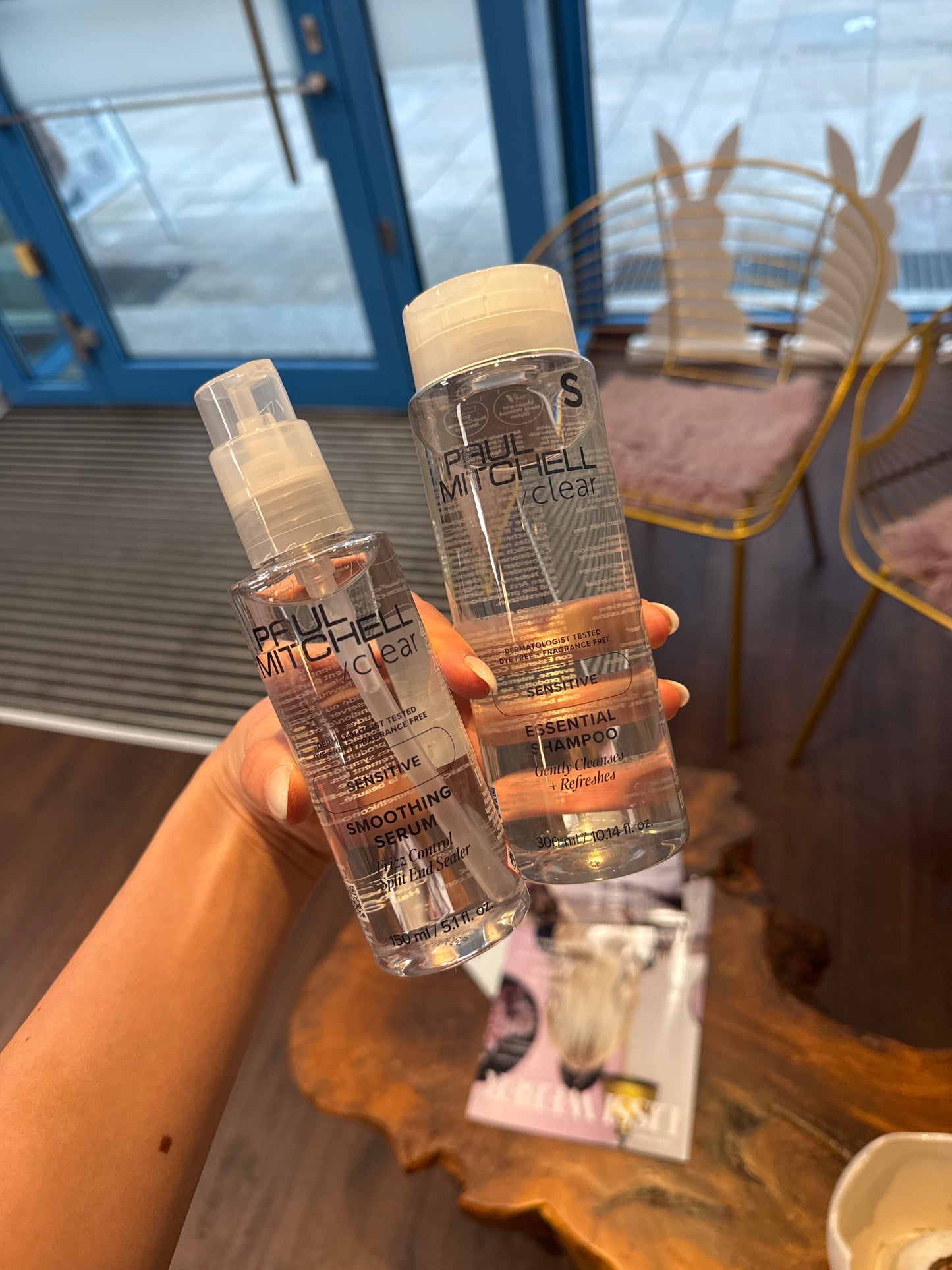 Smoothing Serum und Essential Shampoo für empfindliche Kopfhaut in Hand im Salonbereich – Paul Mitchell