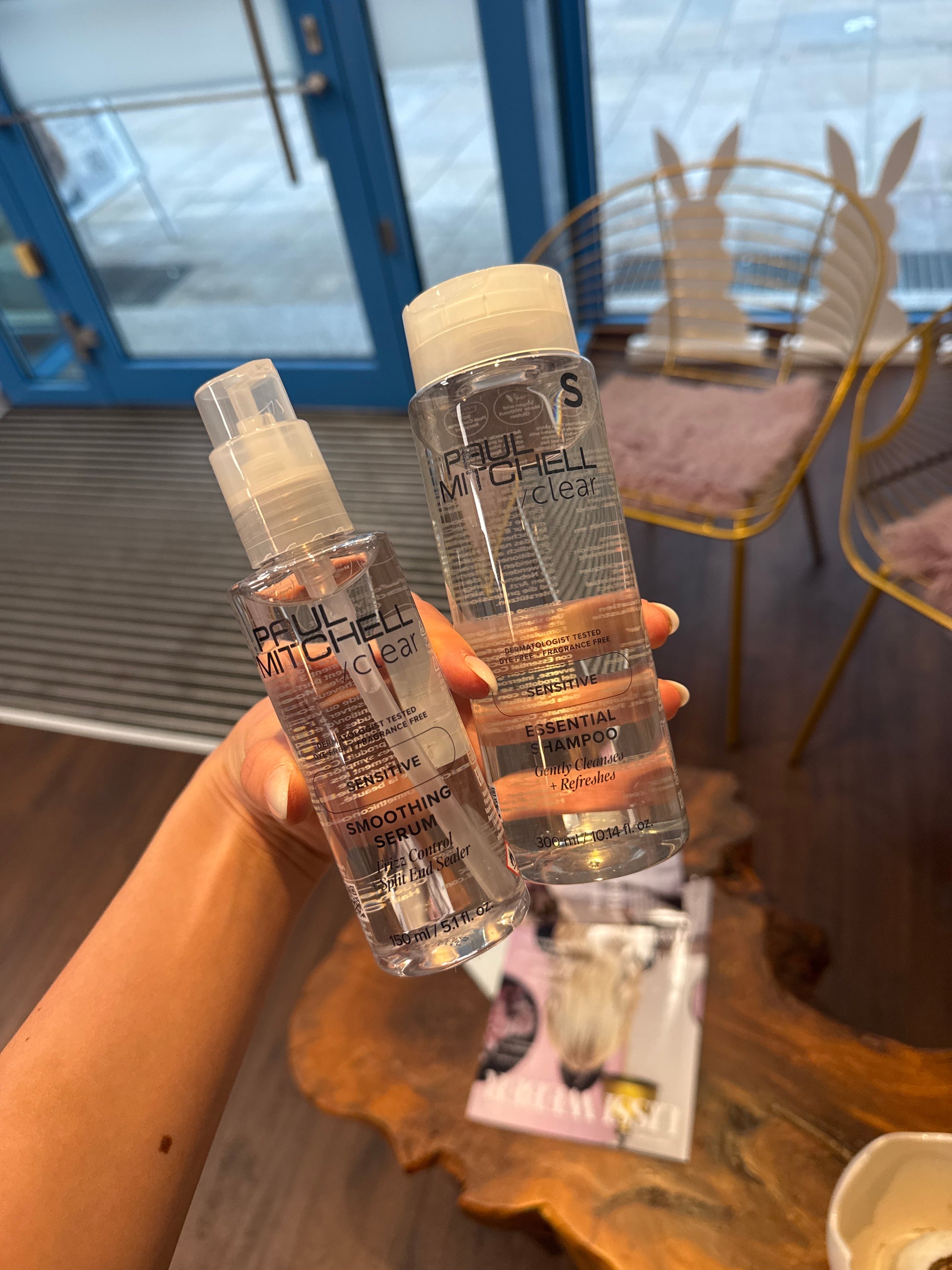 Smoothing Serum und Essential Shampoo für empfindliche Kopfhaut in Hand im Salonbereich – Paul Mitchell