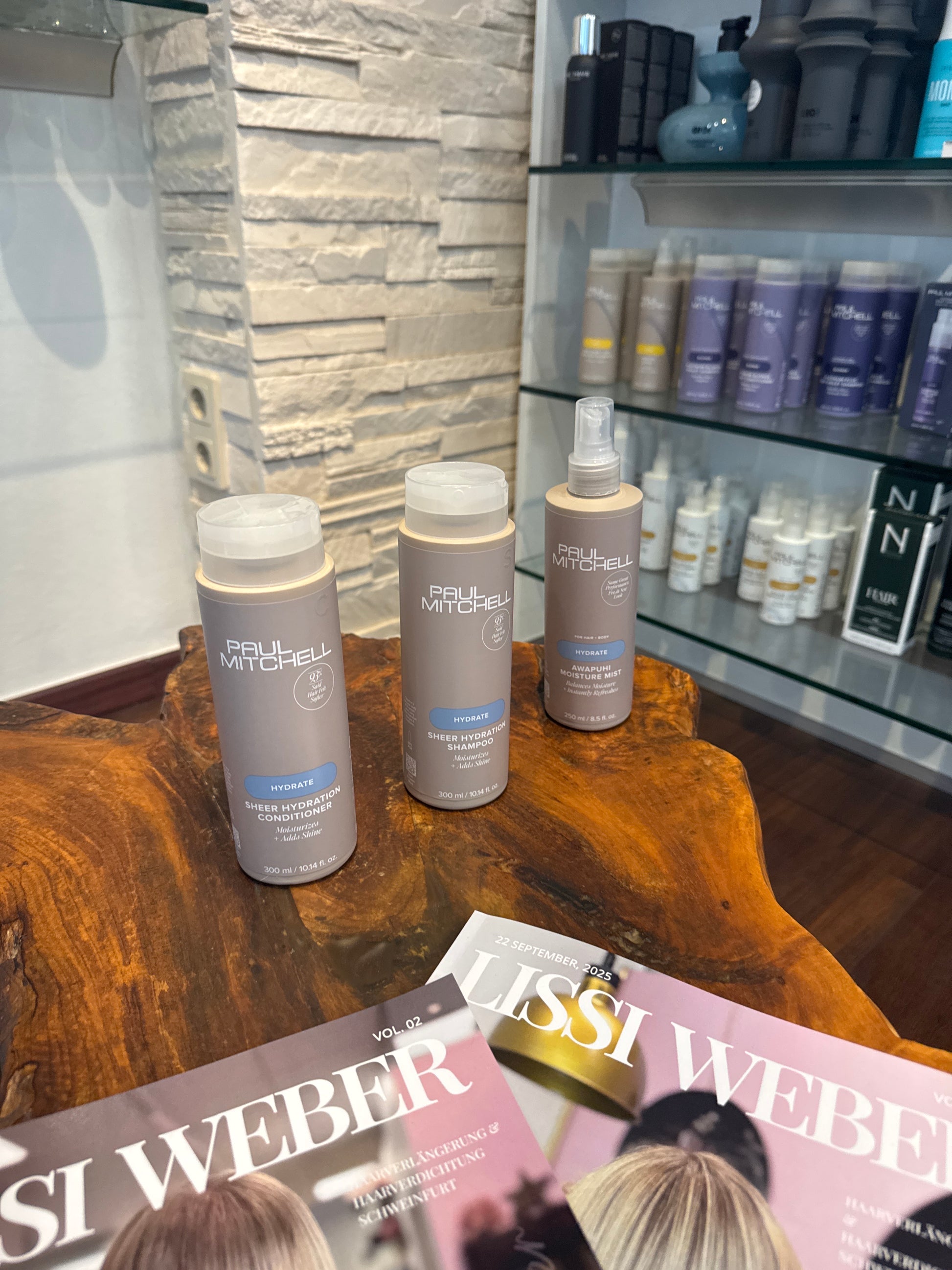 Hydrate Shampoo Conditioner und Feuchtigkeitsspray für trockenes Haar im Set auf Holztisch im Salon – Paul Mitchell