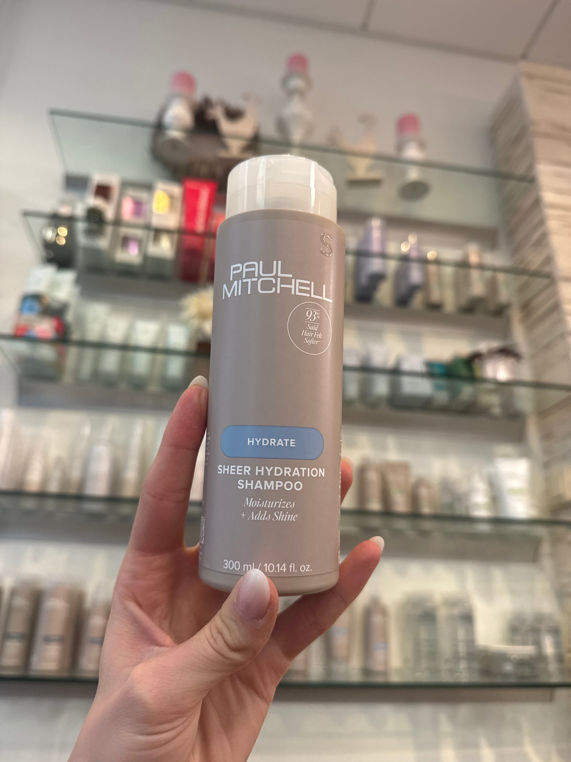 Sheer Hydration Shampoo Feuchtigkeitsshampoo für trockenes Haar in Hand vor Produktregal im Salon – Paul Mitchell