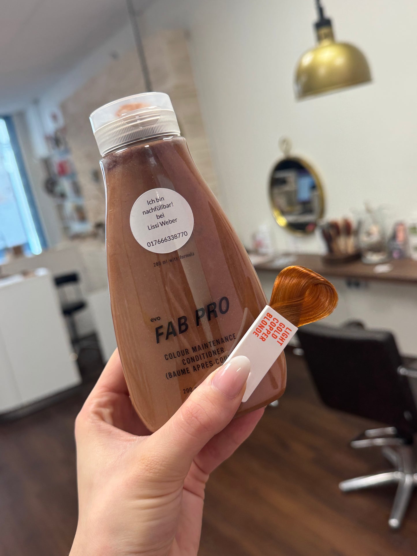 FAB Pro Conditioner brauner Farbton mit Farbmuster im Friseursalon, nachfüllbare Pflegeflasche in der Hand – Evo