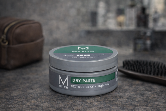 Mitch Dry Paste Texture Clay mit Lederetui Bürste und Kerze auf dunklem Untergrund – Paul Mitchell
