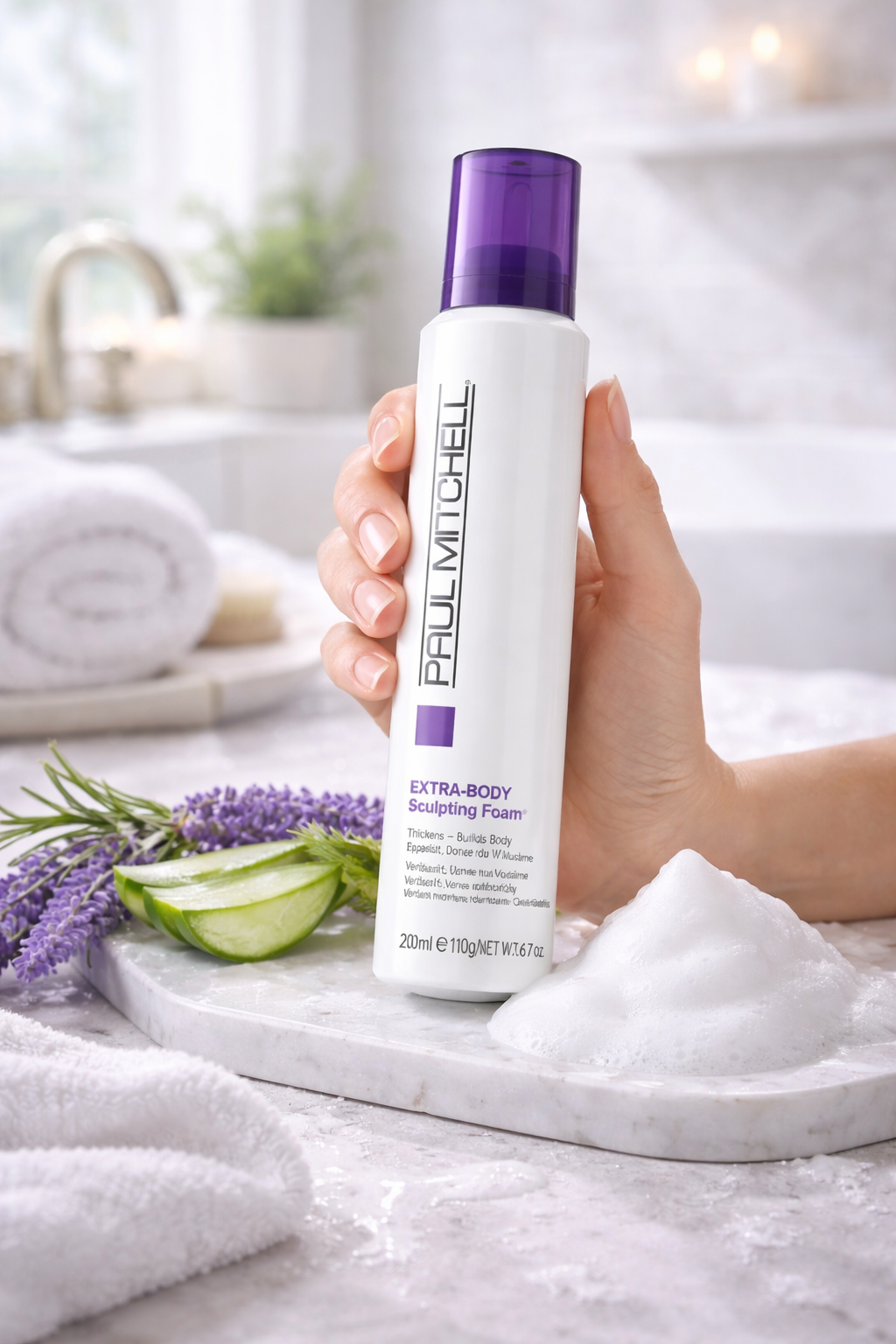 Extra Body Sculpting Foam Volumen Styling Schaum, Produktflasche in der Hand vor hellem Badezimmer Hintergrund mit schaum, Paul Mitchell